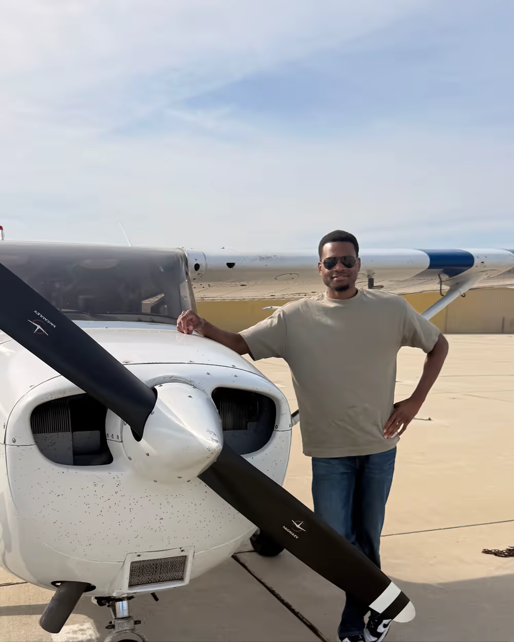 Uche standing beside the training airplane after completing his first solo flight